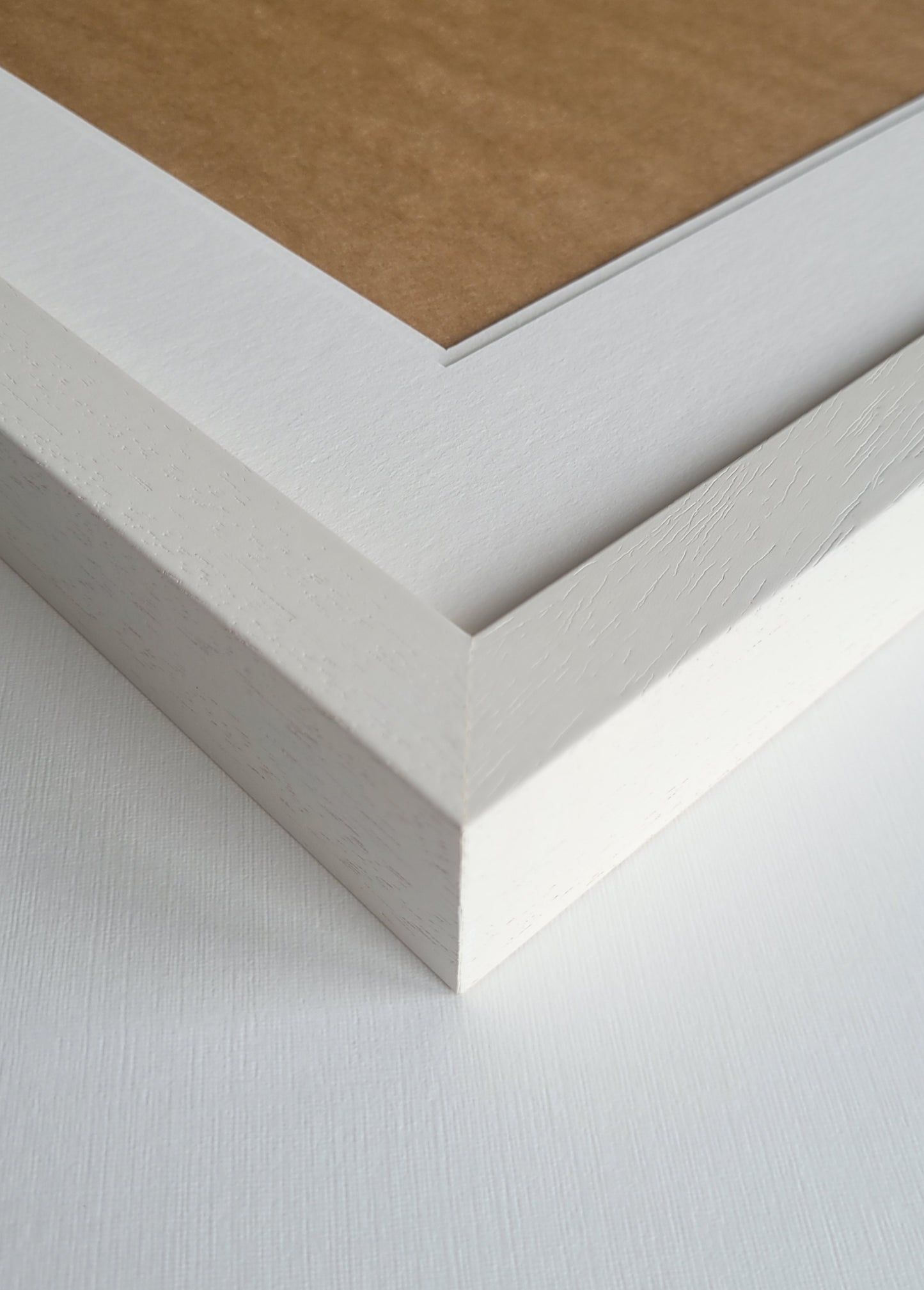 Close-up of a white picture frame corner on a textured white surface