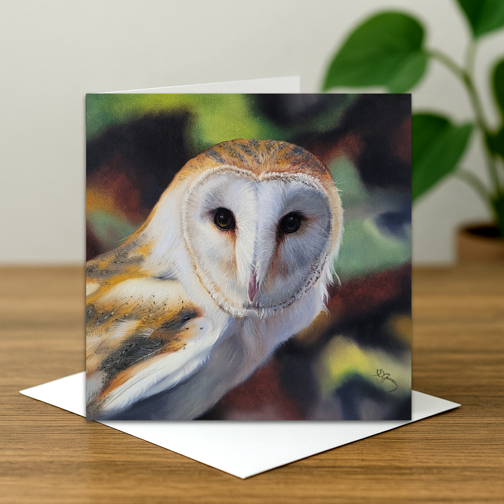 Greeting card with a barn owl design on a wooden surface.