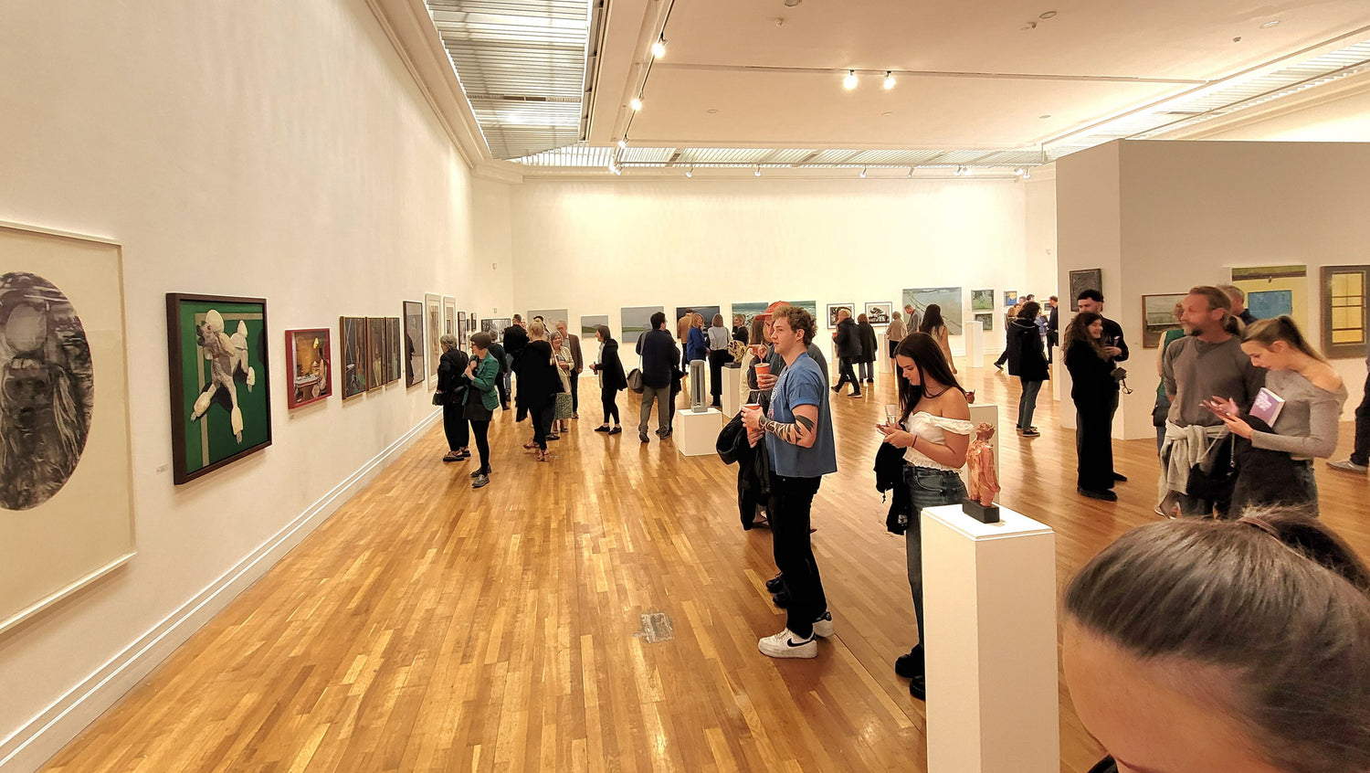 2025 RHA exhibition with visitors looking at artworks on the walls.
