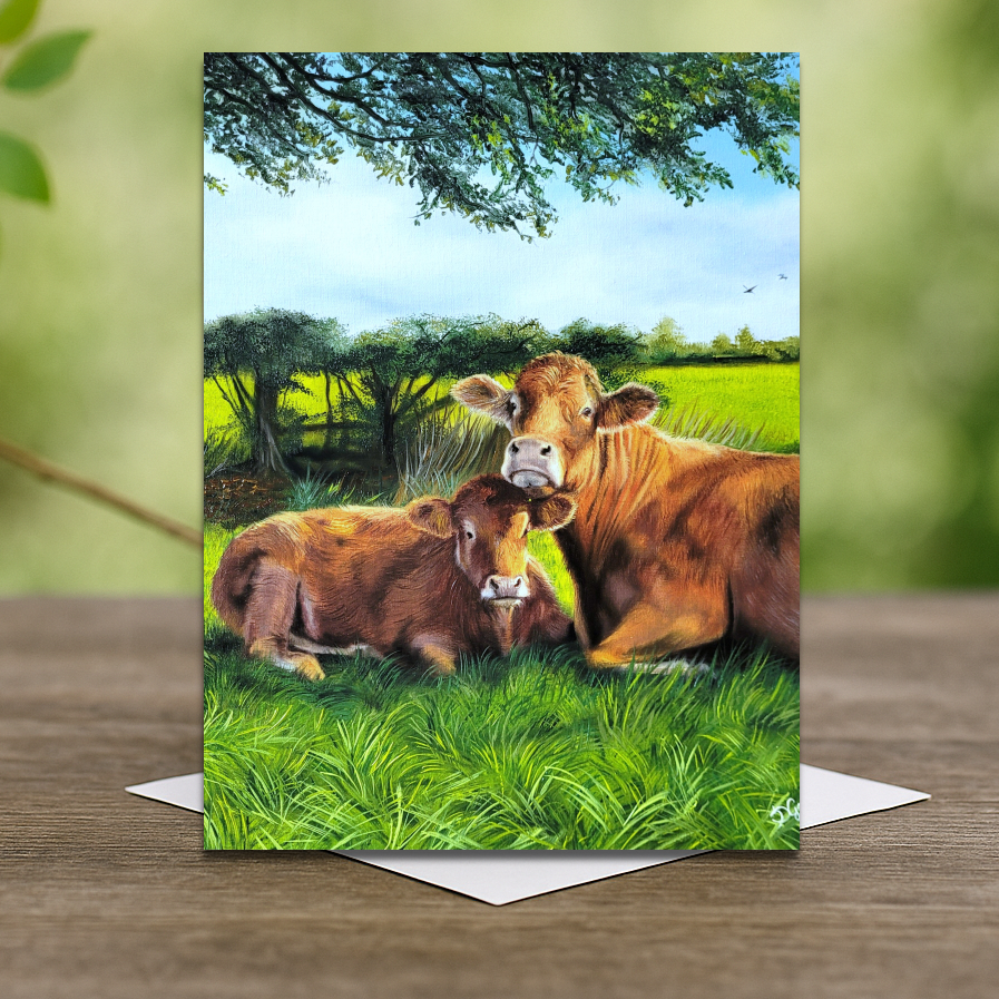 Greeting card with two cows in a pastoral scene on a wooden surface.