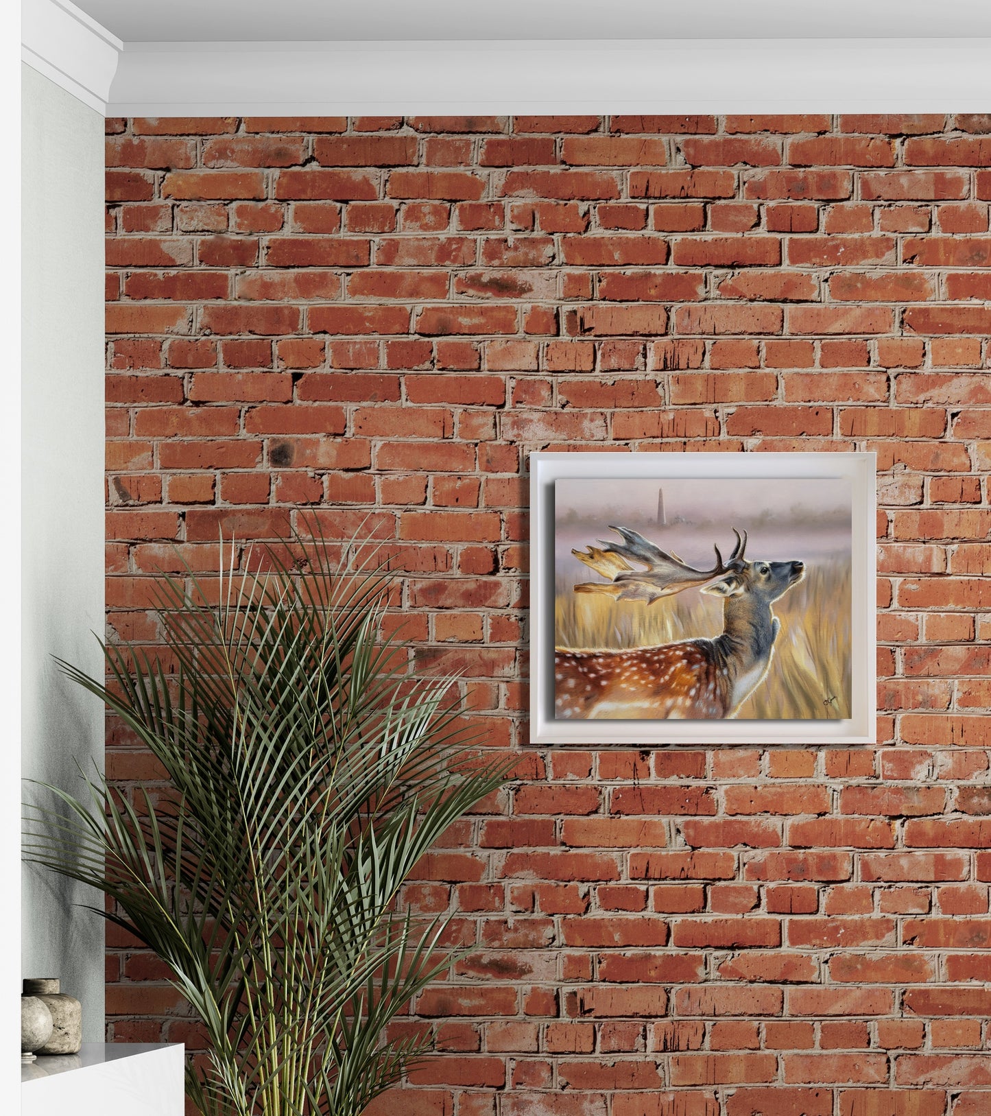 Framed deer painting on a red brick wall
