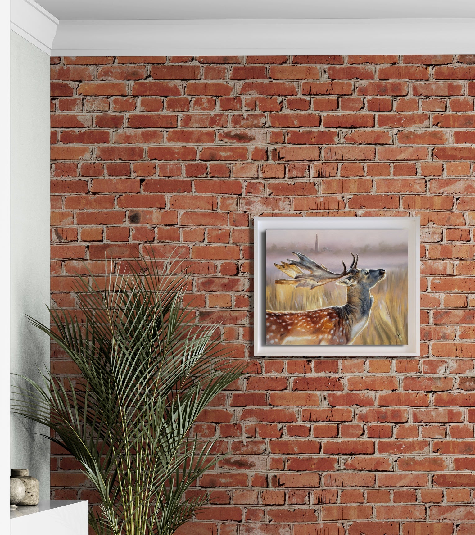 Framed deer painting on a red brick wall