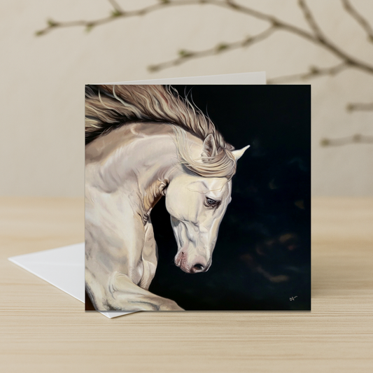 Greeting card with a painting of a white horse on a dark background, placed on a wooden surface.